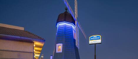 A hotel with a distinctive windmill-like structure, a signboard, and a well-lit entrance.