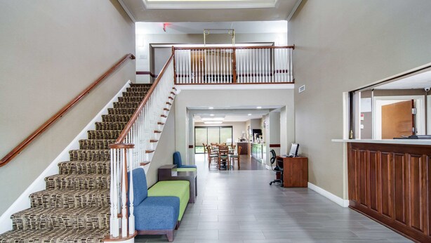 A spacious foyer with a staircase leading to a second floor, a reception desk, and a seating area with chairs and a sofa. - Quality Inn & Suites Canton, GA (Canton)