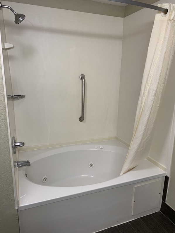 A white bathtub with a showerhead, a grab bar, and a curtain.