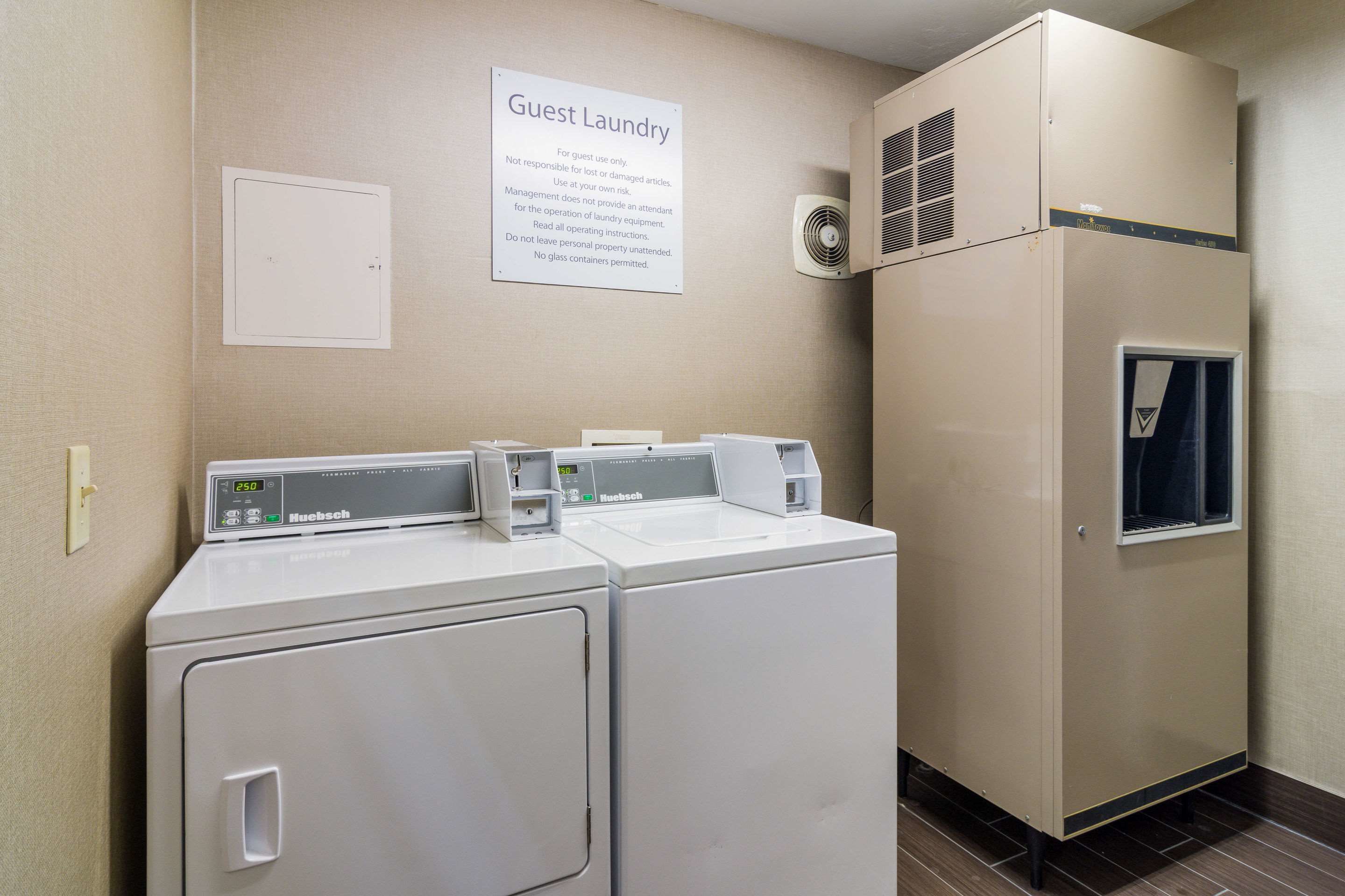 A laundry area with two front-loading machines, a wall-mounted dryer, and a sign indicating it's for guest use only.