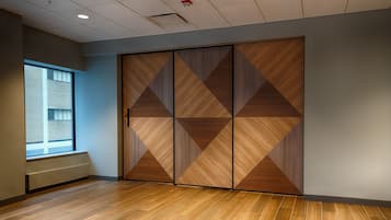 A room with a large sliding door, a window with blinds, and a wooden floor.