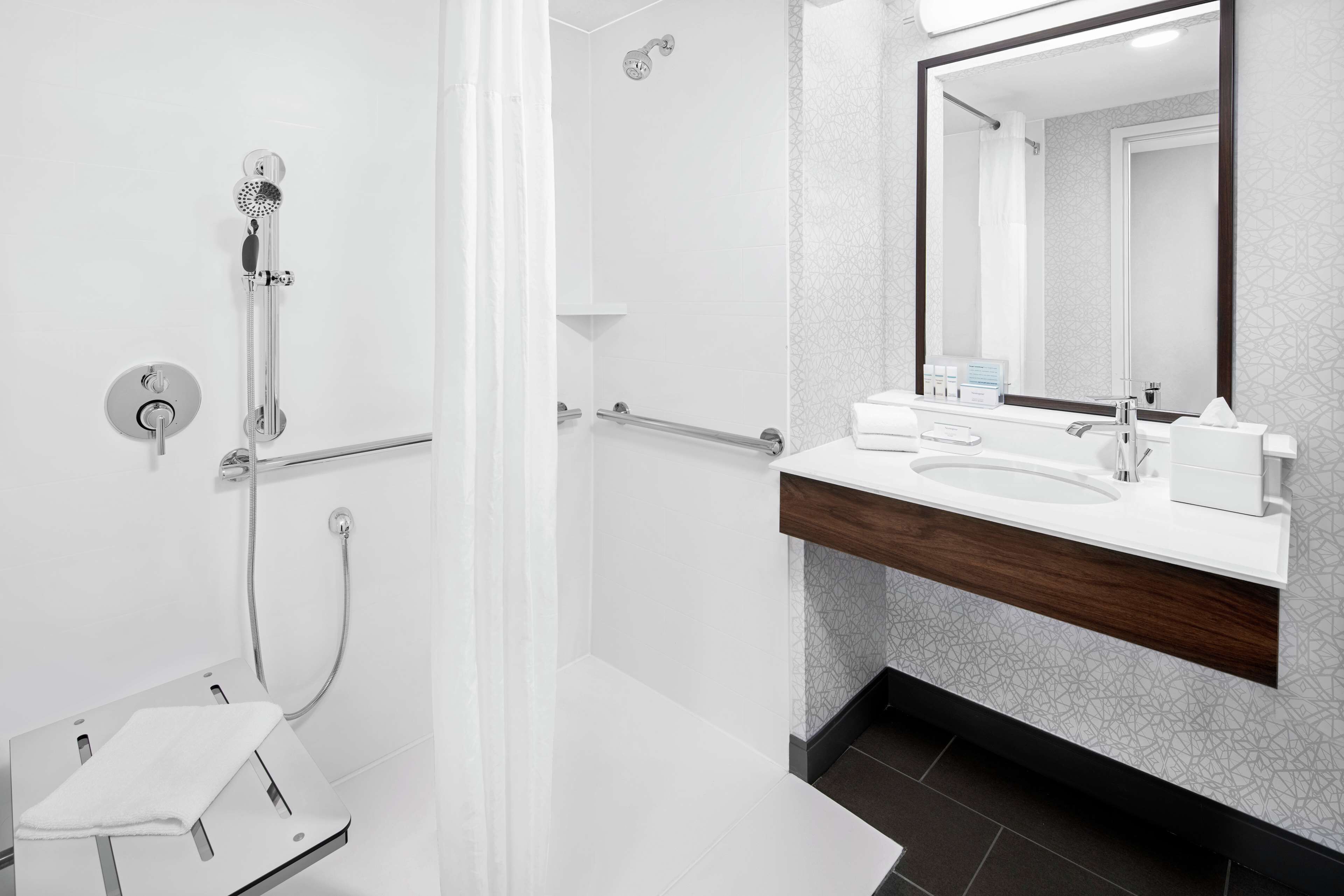 Une salle de bain moderne avec une douche, un lavabo et un miroir.