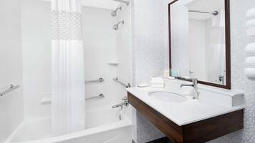 Een moderne badkamer met een bad, douche en een wastafelmeubel met wastafel en spiegel.