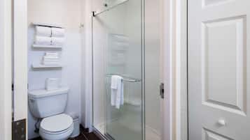 A bathroom with a toilet, a glass shower enclosure, and a towel rack.