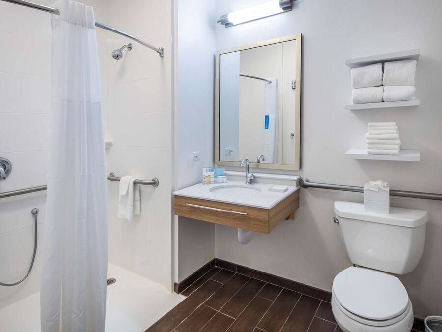 A bathroom with a shower, sink, toilet, and towel racks.