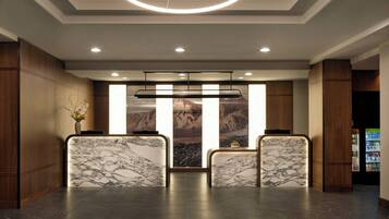A reception area with marble reception desks, a modern chandelier, and a mountain view through the glass doors.