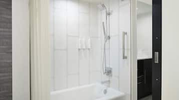 Et moderne badeværelse med badekar, brusebad og hvide fliser.