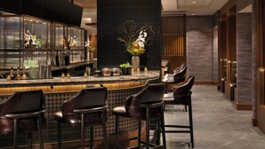 A bar area with a curved counter, multiple stools, and a decorative vase with flowers. - Las Vegas Marriott (Las Vegas)
