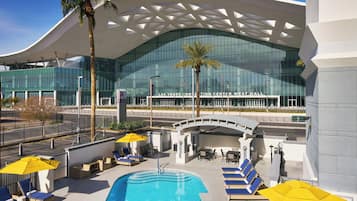 Een buitenzwembad, ligstoelen bij het zwembad