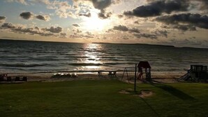 Une plage avec une structure en bois, une zone herbeuse et l’océan.