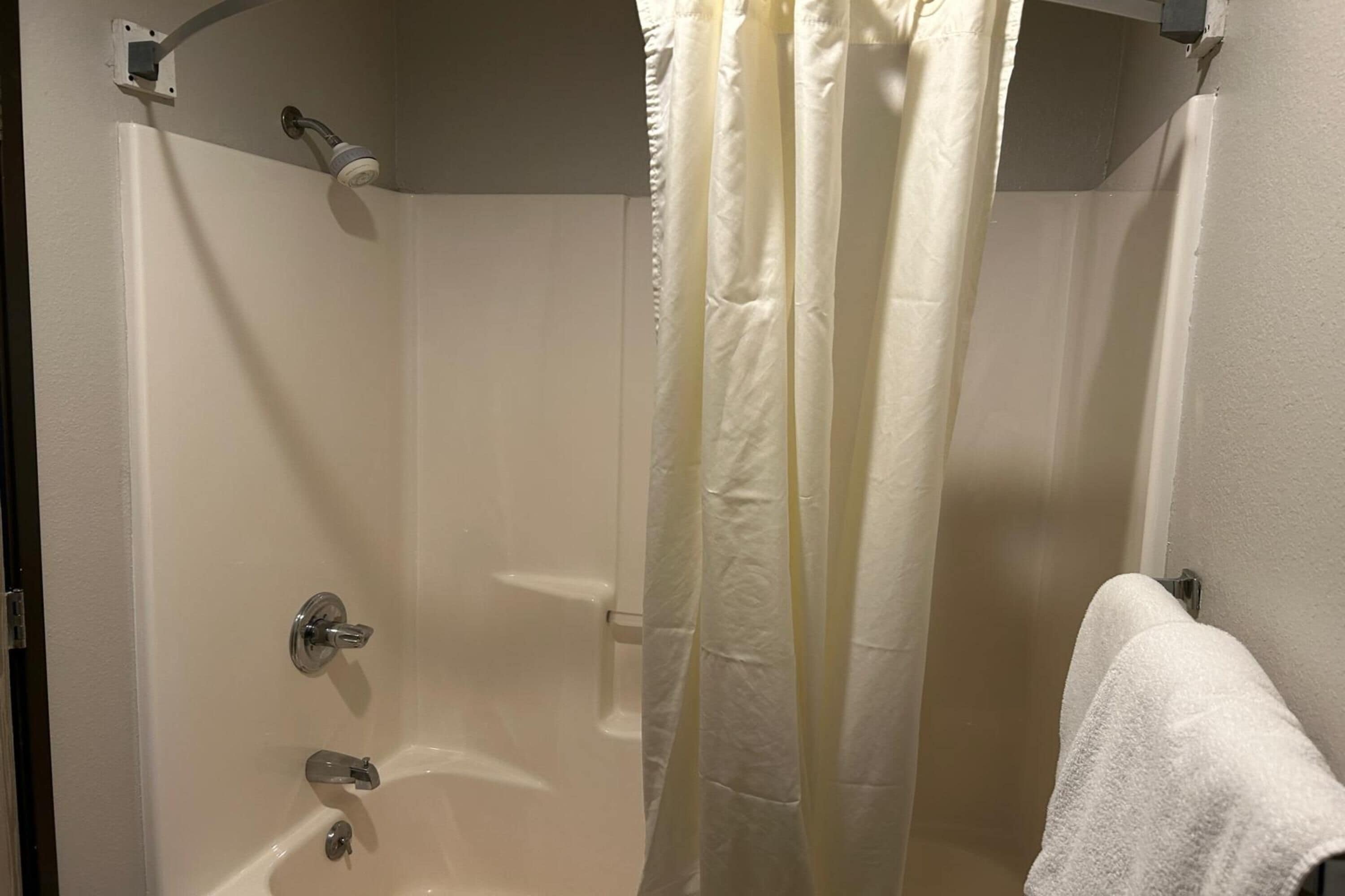 A bathroom with a bathtub, a shower, and a towel rack.
