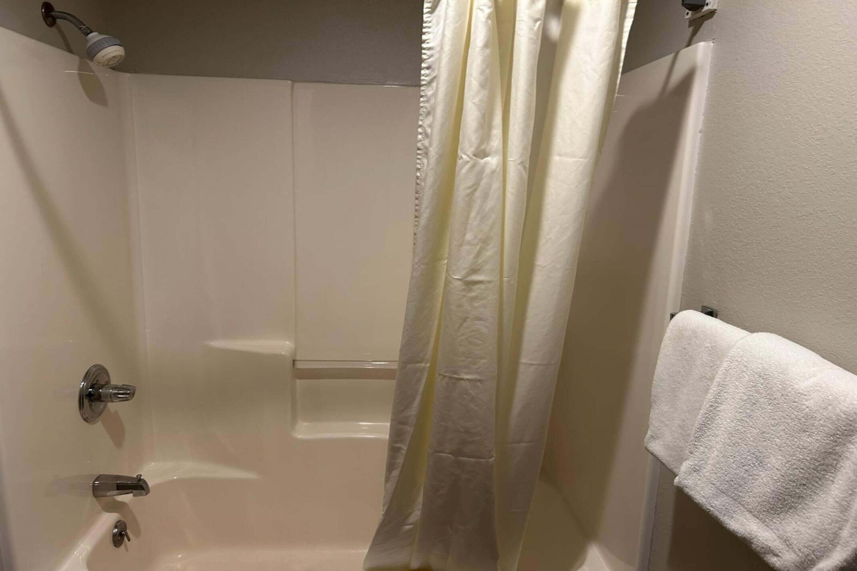 Une salle de bain avec une baignoire, un rideau de douche et un porte-serviettes.