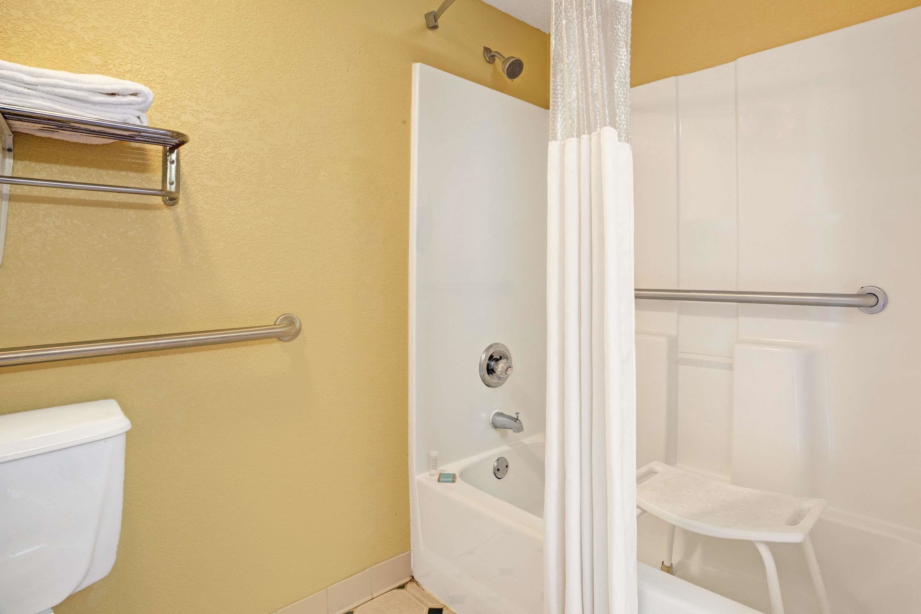 A bathroom with a shower, toilet, and a towel rack.