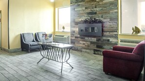 A room with a stone wall, a table with chairs, and a red armchair.
