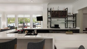 A modern kitchen with a large island, wine rack, and a flat-screen TV. - Hilton Garden Inn Tallahassee (Tallahassee)
