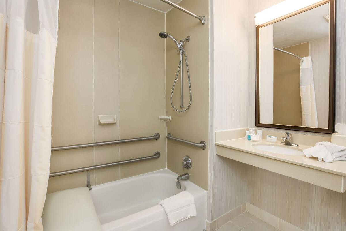 A bathroom with a bathtub, shower, and vanity with a mirror.
