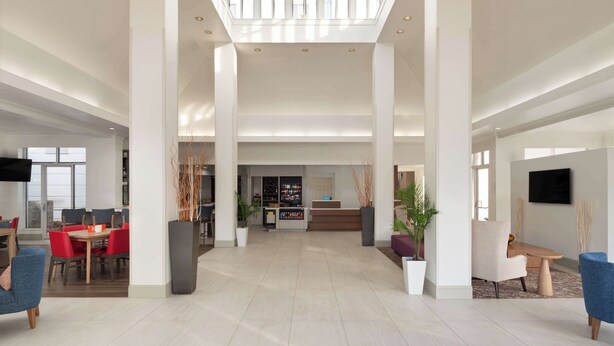 A spacious lobby with high ceilings, a central reception desk, and seating areas. - Hilton Garden Inn Tallahassee (Tallahassee)