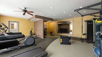 A gym with treadmills, exercise bikes, and a ceiling fan.
