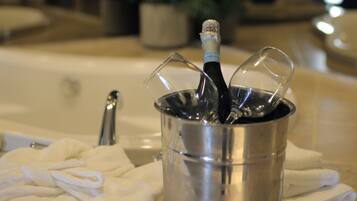 Una bañera con una botella de champán en un balde, rodeada de toallas blancas.