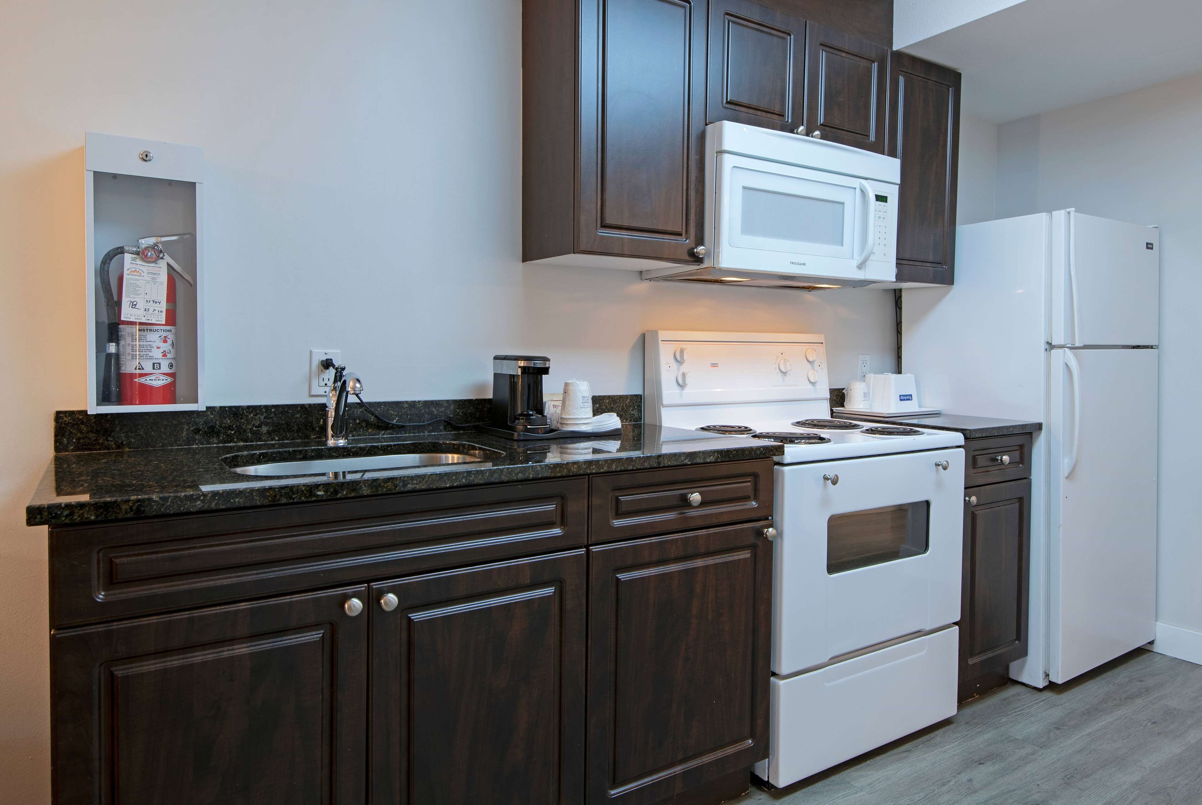 Una cocina moderna con alacenas de madera oscura, una estufa blanca, un microondas y un refrigerador.