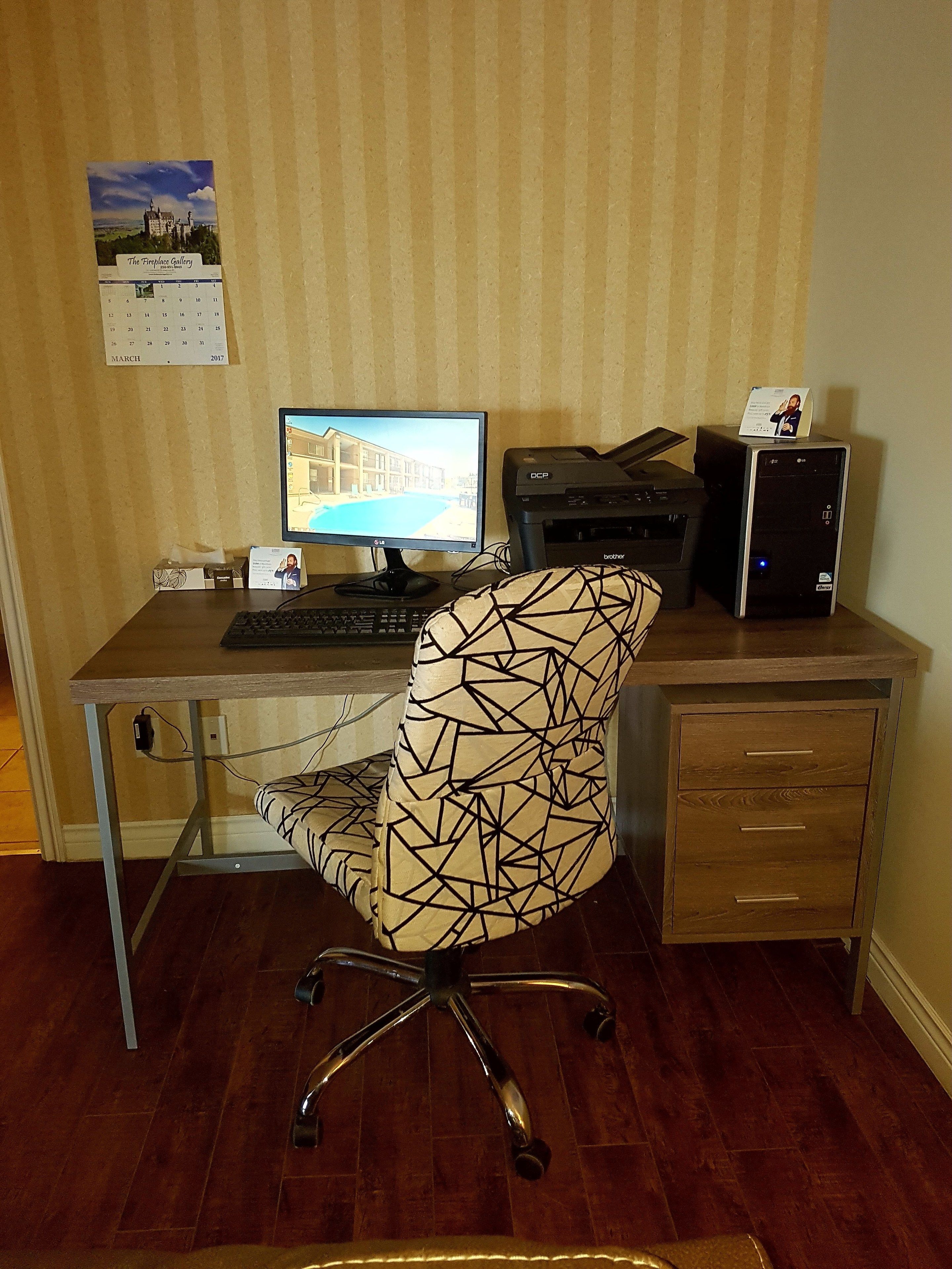 A home office setup with a computer, printer, and a calendar on the wall.