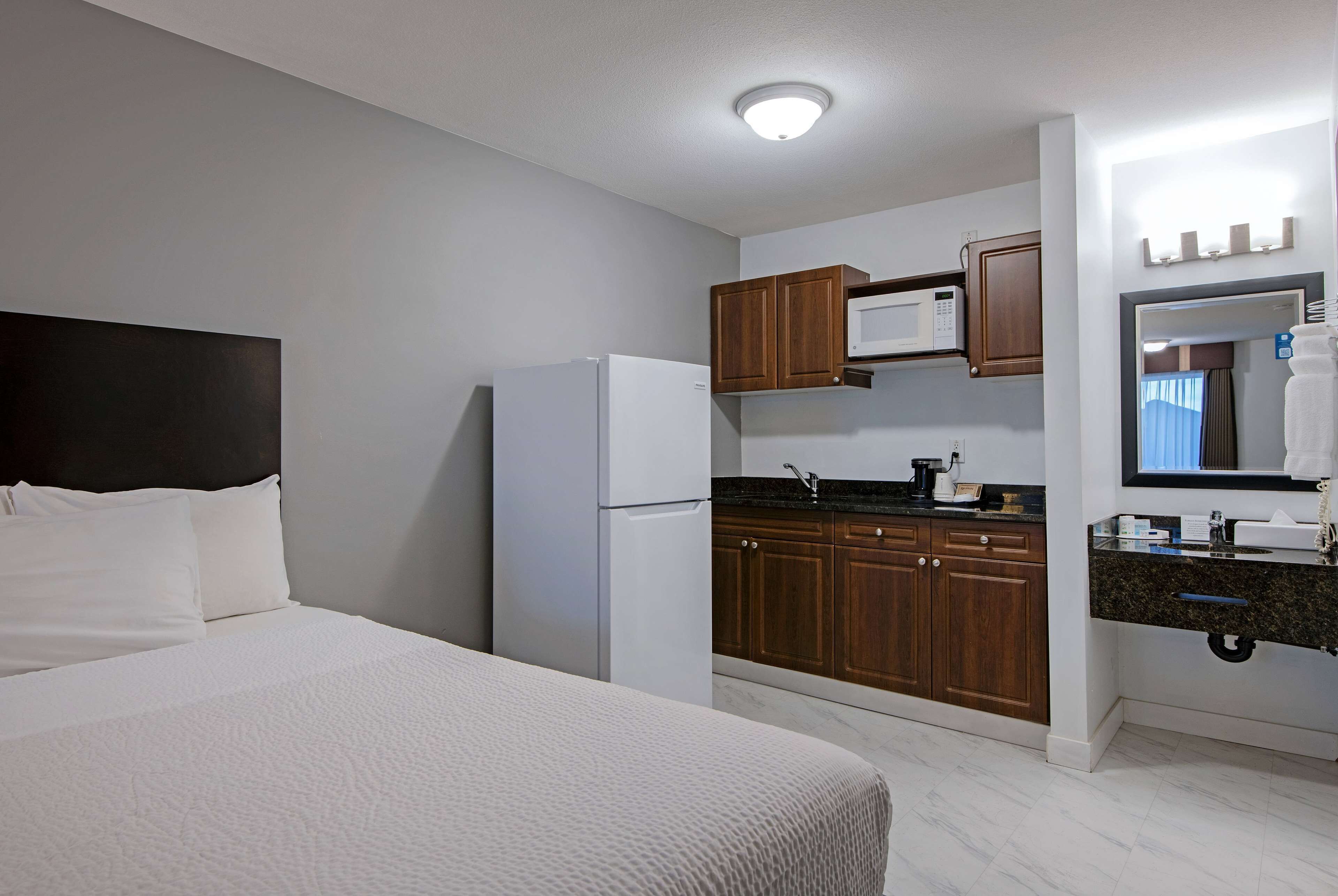 Une chambre d’hôtel équipée d’un lit, d’une kitchenette, d’un four à micro-ondes et d’un évier.