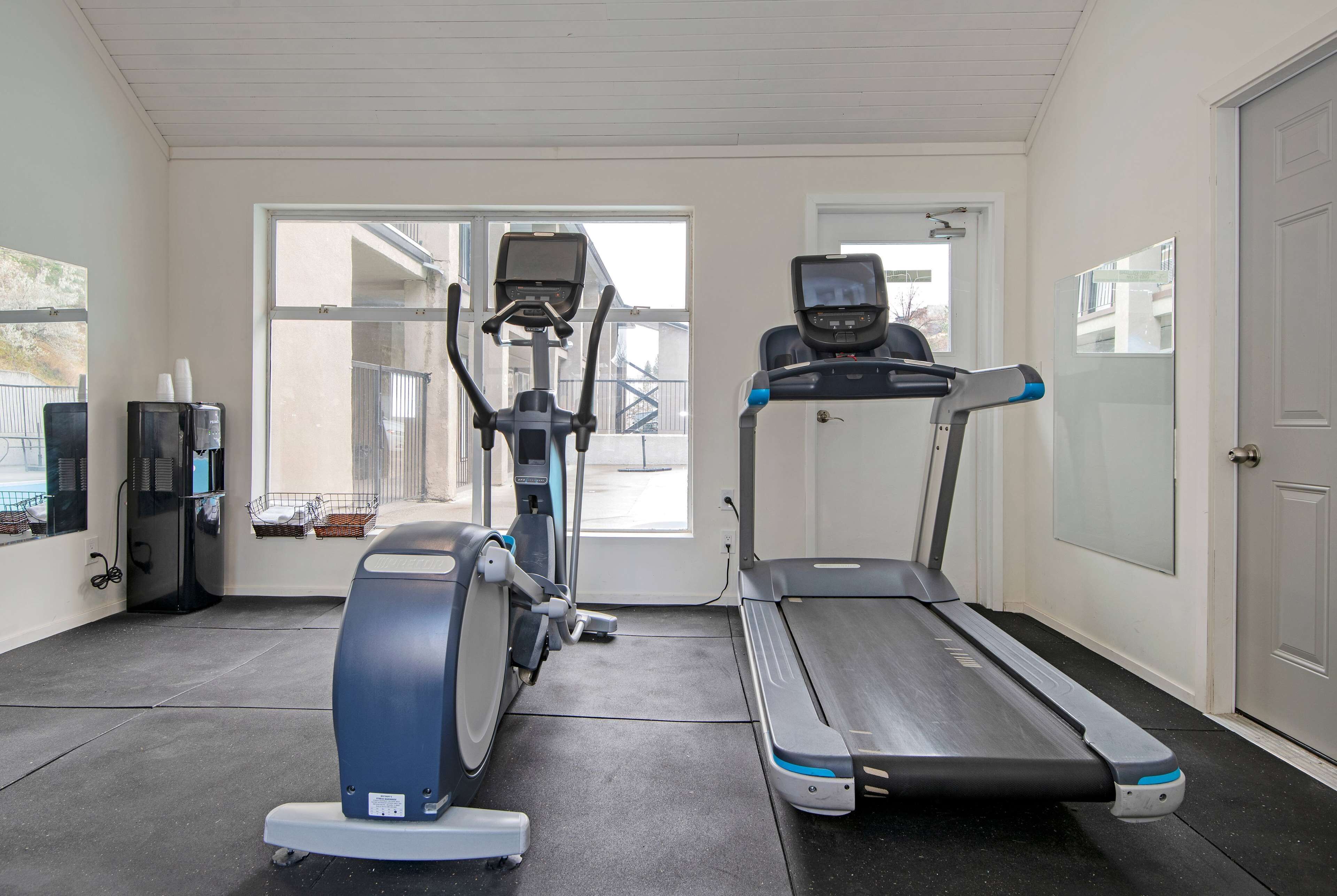 A gym with a treadmill, elliptical, and stationary bike.