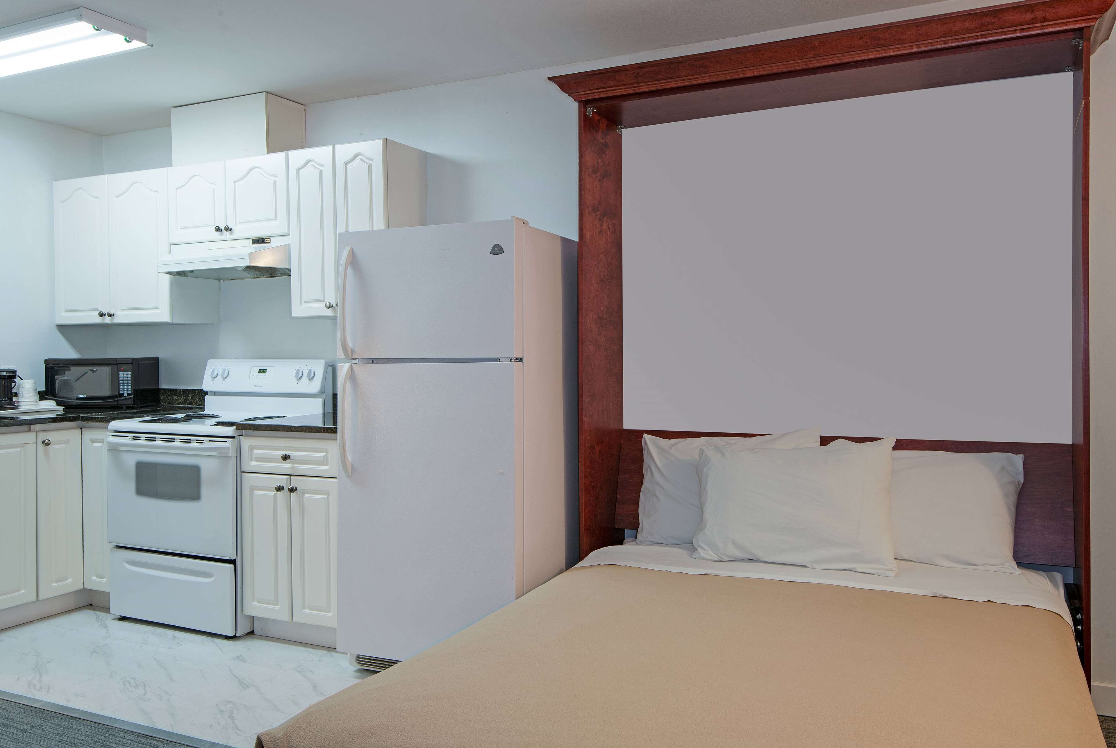 A compact hotel room with a kitchenette, including a stove, microwave, and refrigerator.