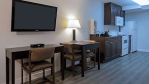 A compact kitchen with a dining area, a flat-screen TV, a lamp, and a microwave.