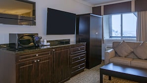 A modern kitchen with dark wood cabinets, a built-in microwave, and a large window with a view of a snowy landscape.