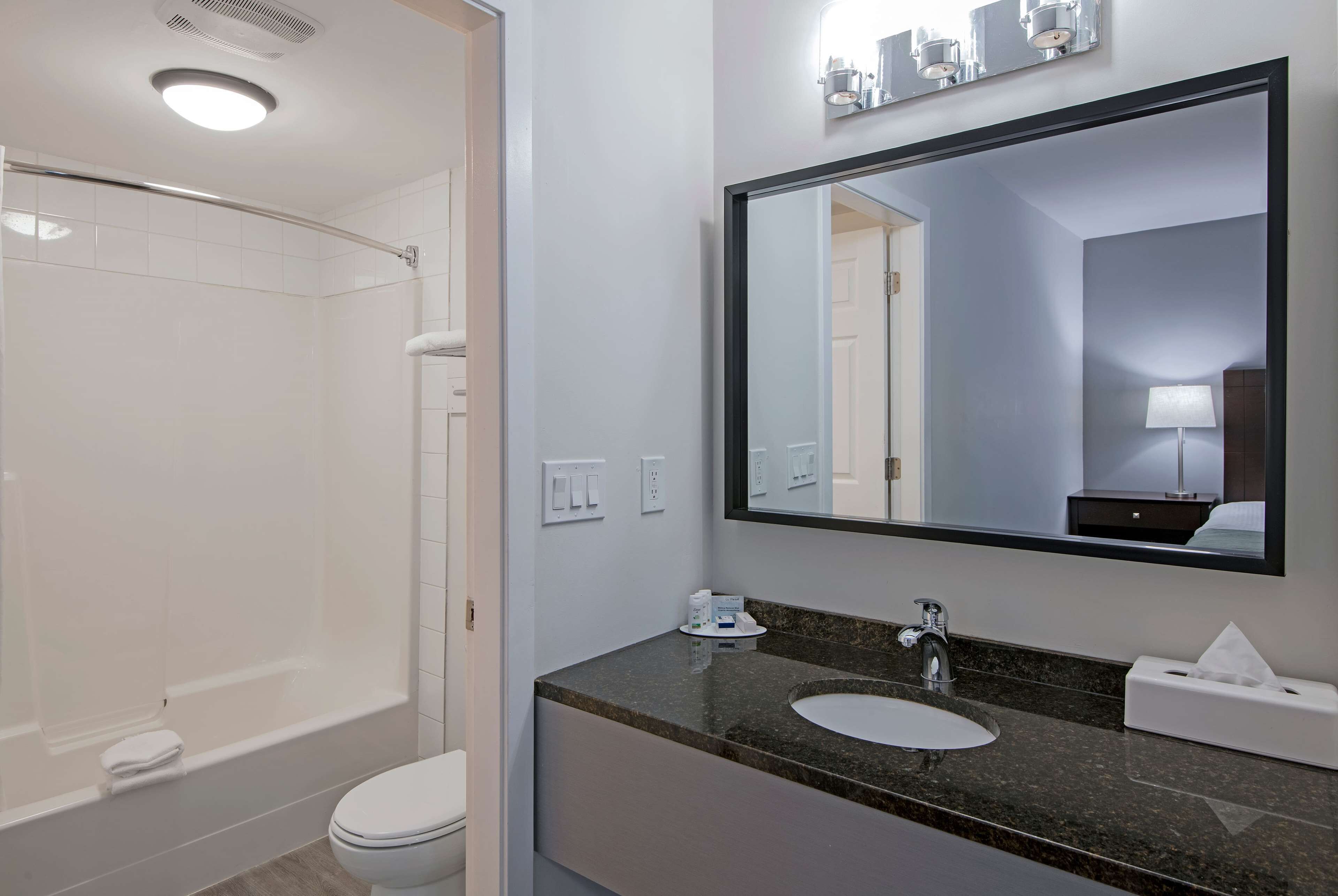 A modern bathroom with a walk-in shower, a sink with a marble countertop, and a large mirror above the sink.