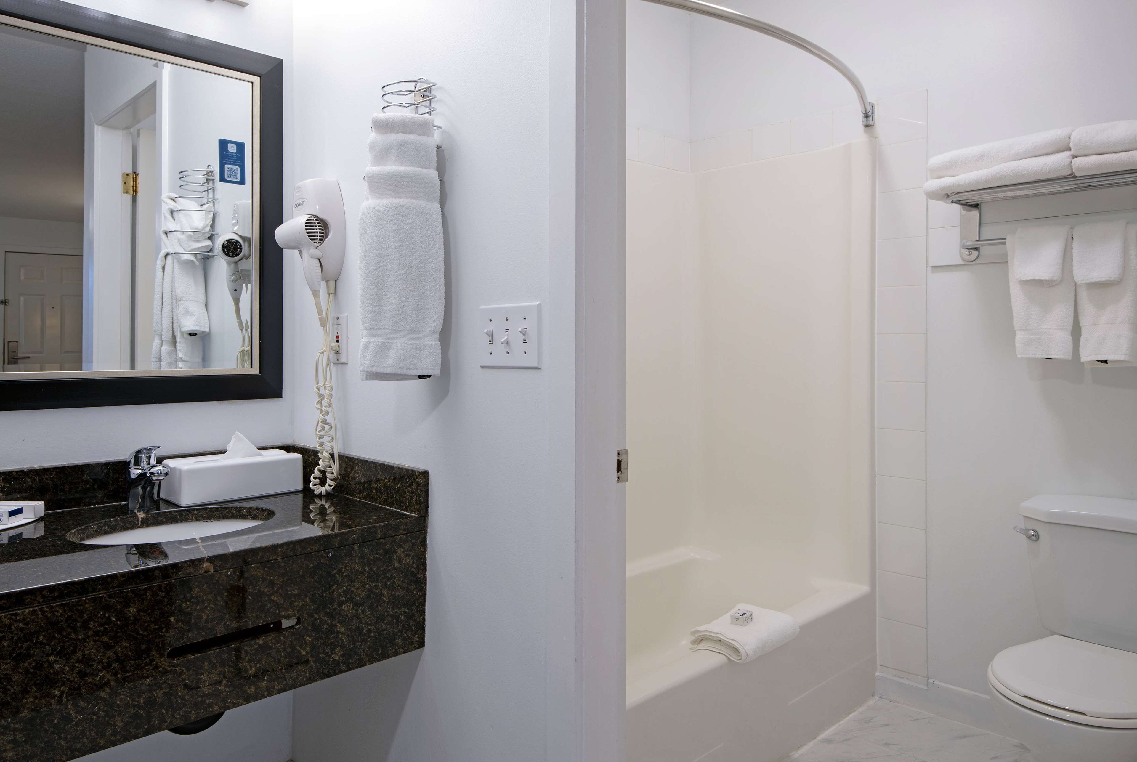 A bathroom with a sink, mirror, towel rack, and a shower area.