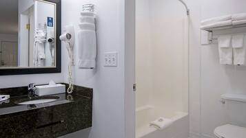 A bathroom with a sink, mirror, towel rack, and a shower area.