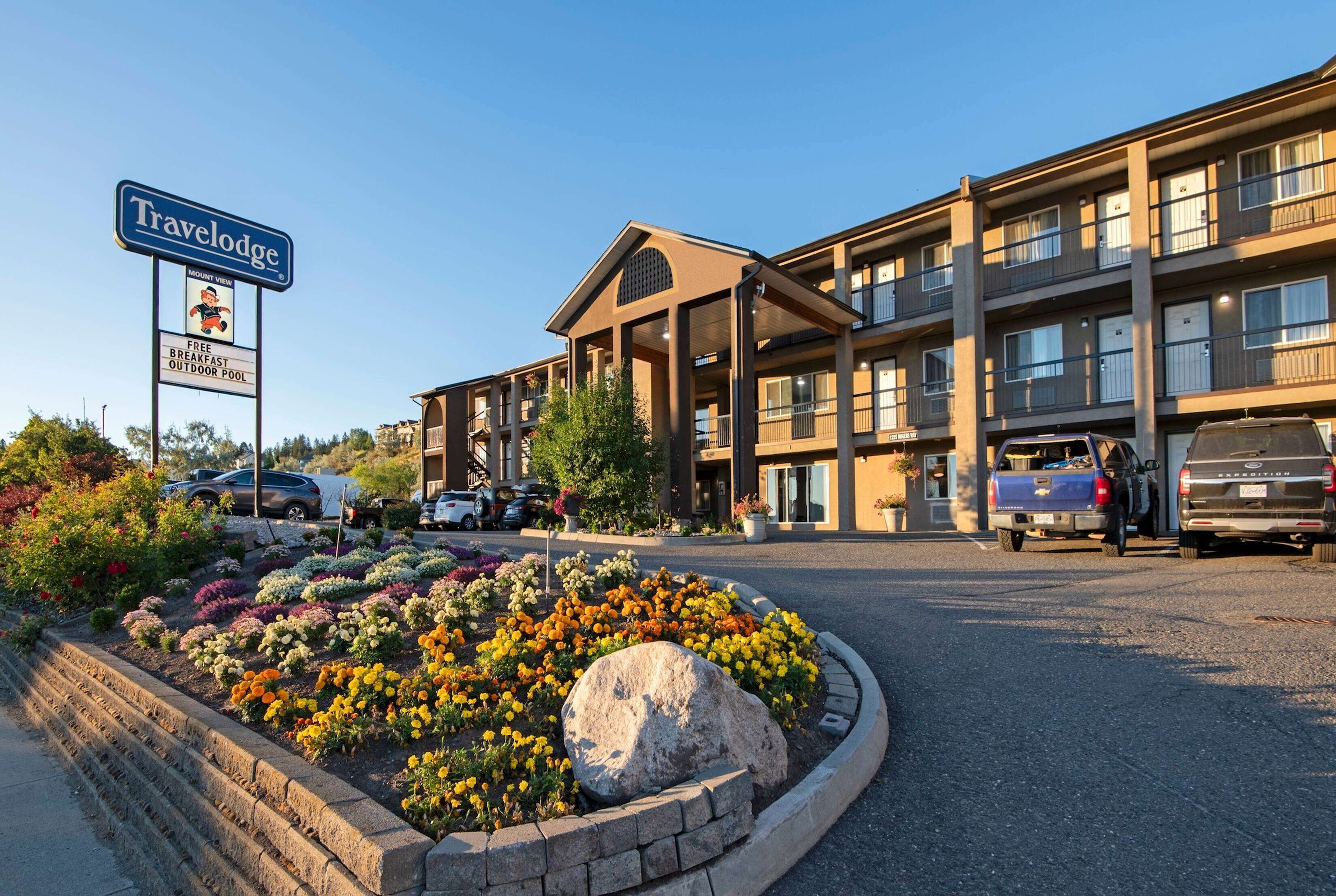A Travelodge hotel with a sign indicating free breakfast and an outdoor pool.