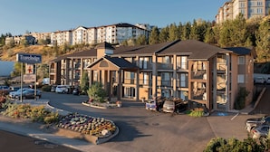 A Travelodge hotel with a parking lot, outdoor pool, and multiple buildings in the background.