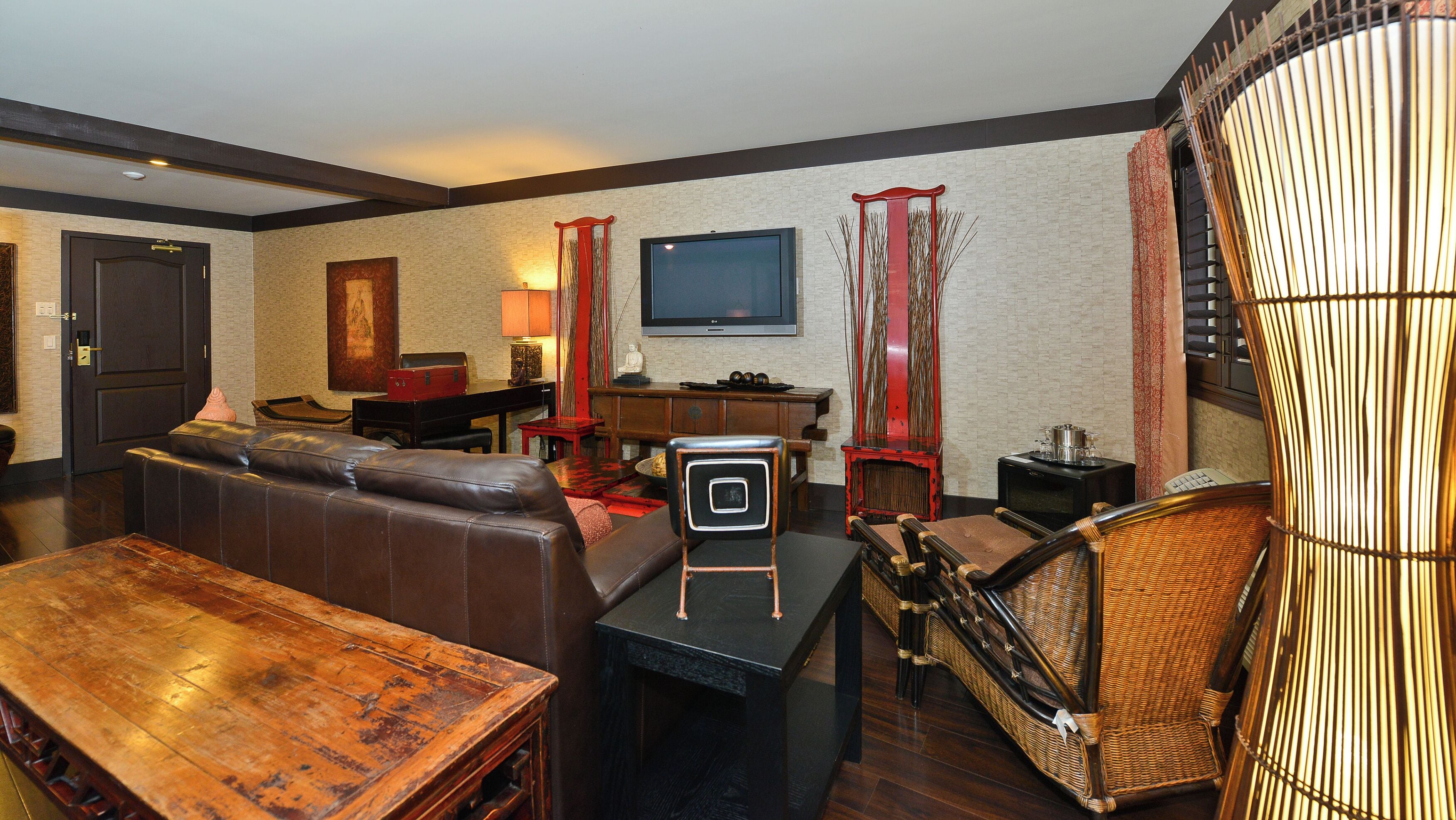 A modern living room with a leather sofa, a wooden coffee table, a television, and a decorative chair.