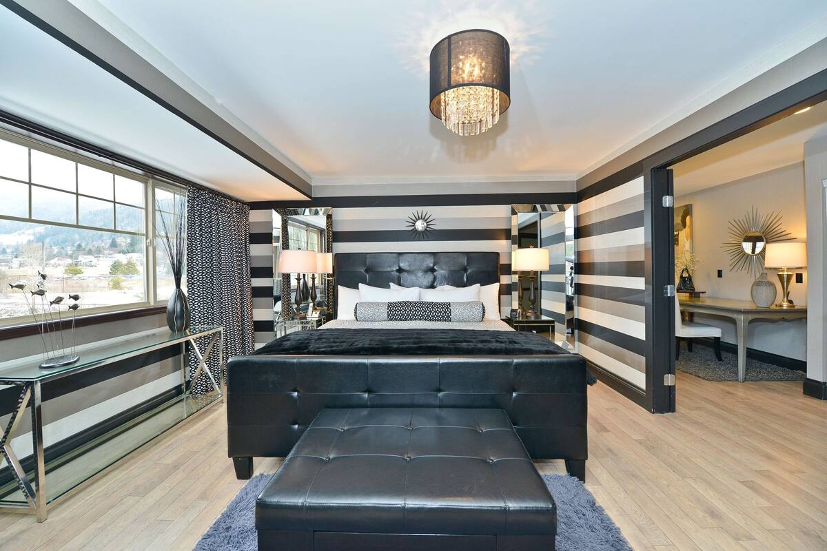 Quarto moderno com uma cama grande, uma escrivaninha de vidro e vista para a cidade.