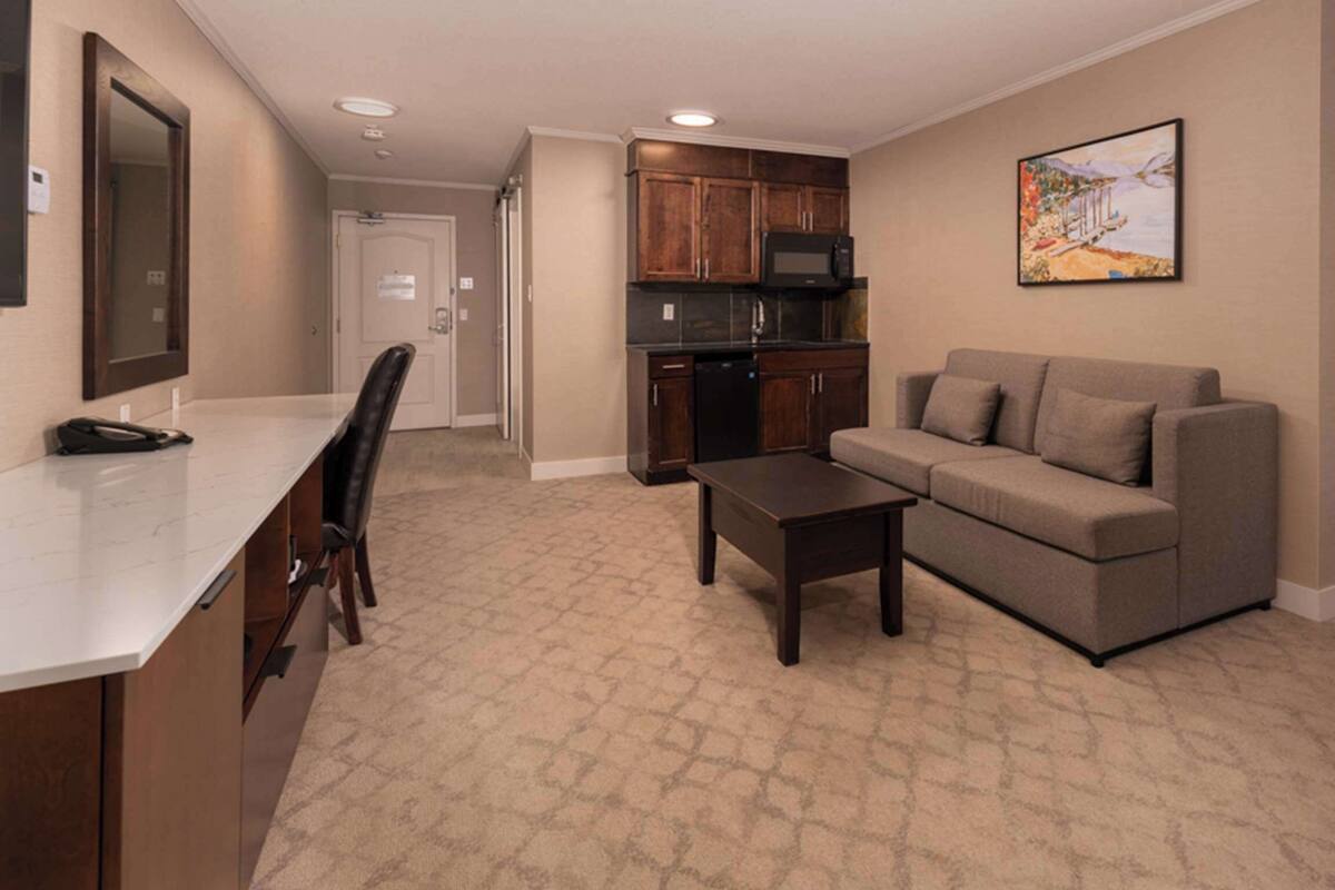 Quarto de hotel com cozinha compacta, sofá, mesa de centro e cama.