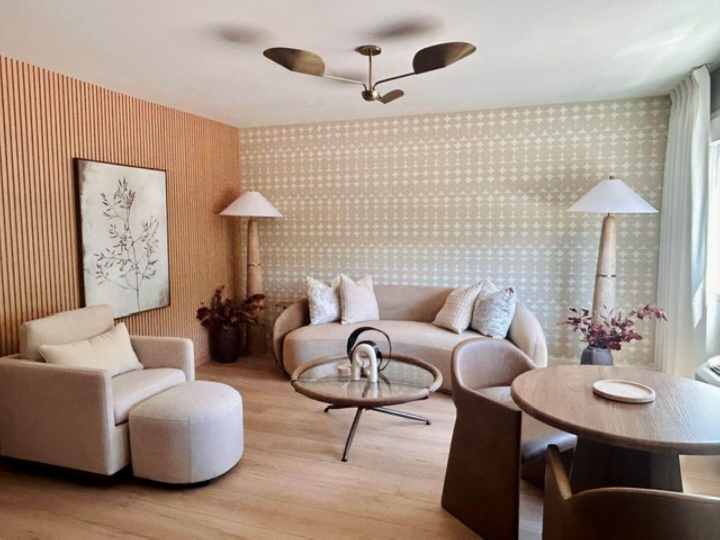 Uma sala de estar moderna com um sofá, poltrona, mesa de centro redonda e um ventilador de teto.