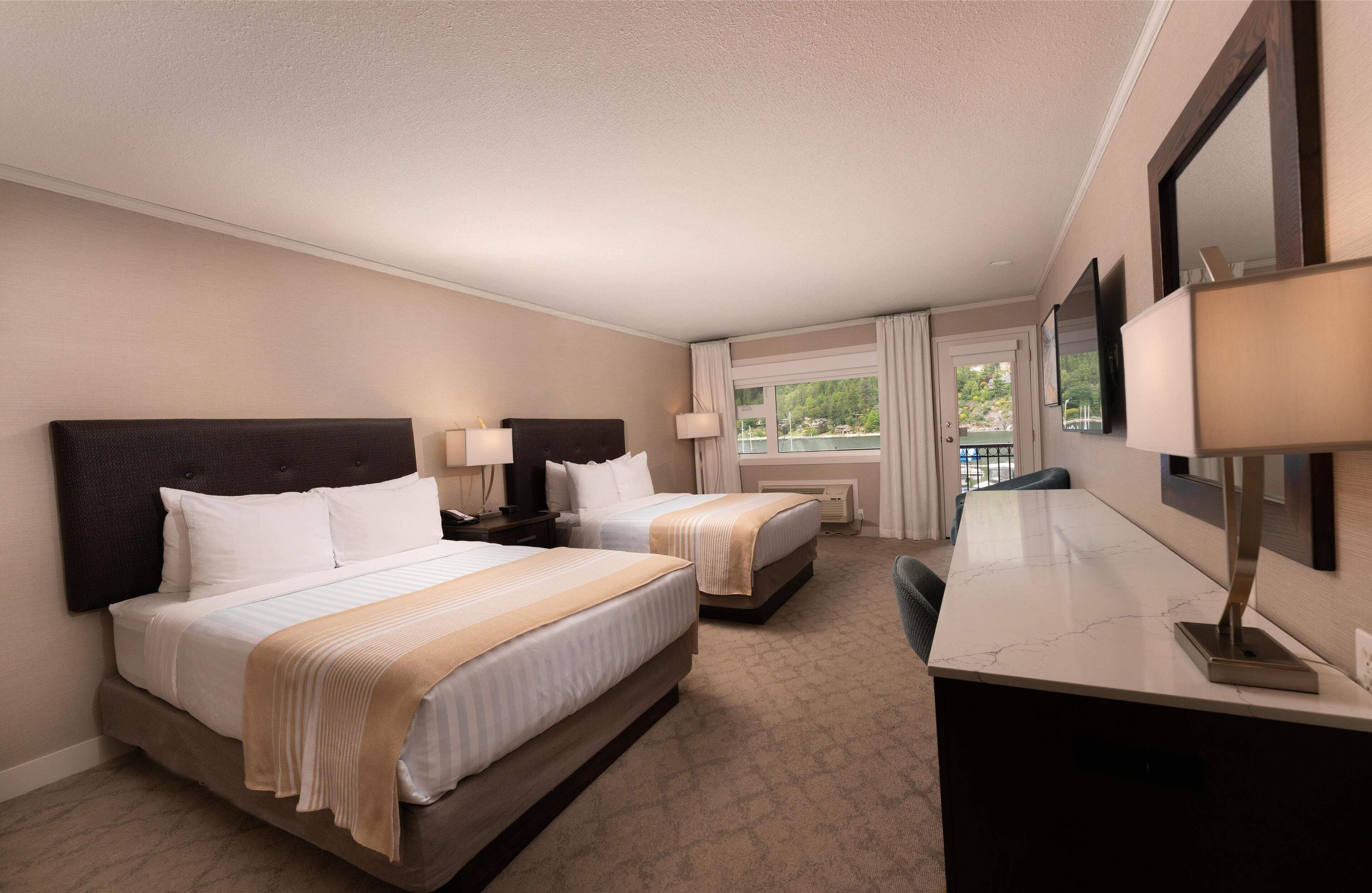 A hotel room with two beds, a desk, and a large window with curtains.
