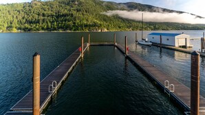 Un muelle de madera que se adentra en un lago tranquilo, rodeado de colinas boscosas.