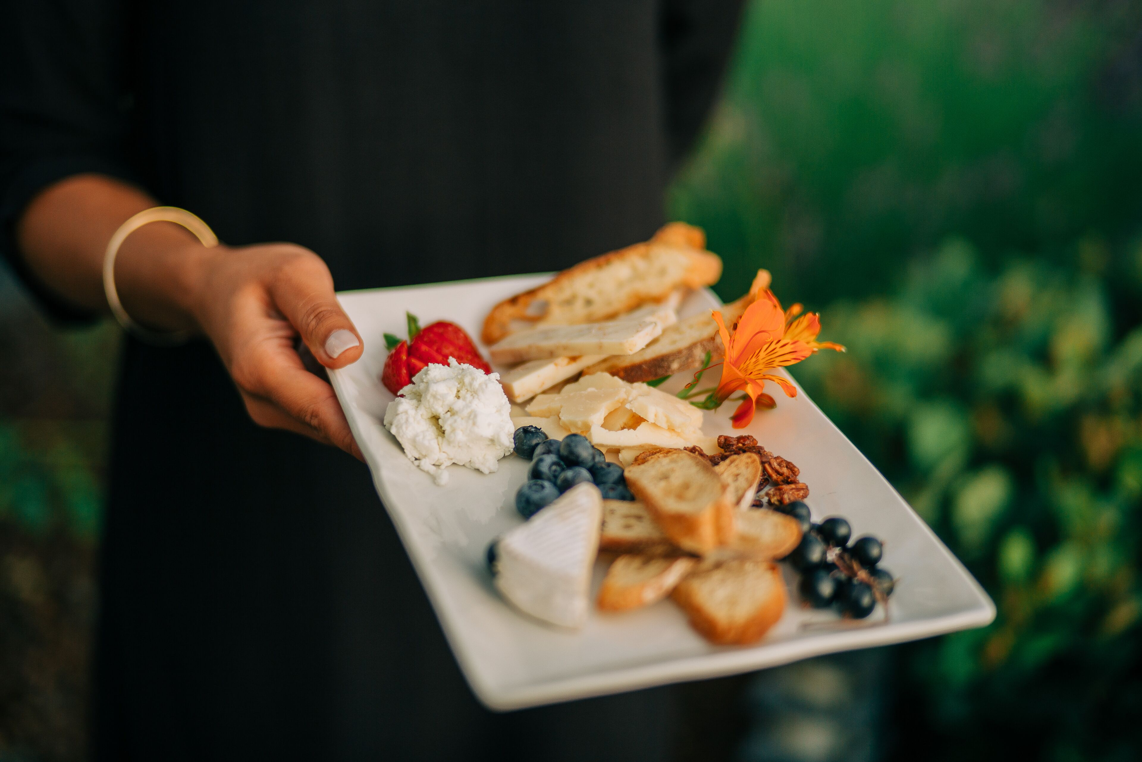 Una persona sosteniendo un plato con diversos alimentos, entre ellos fresas, arándanos y nueces.