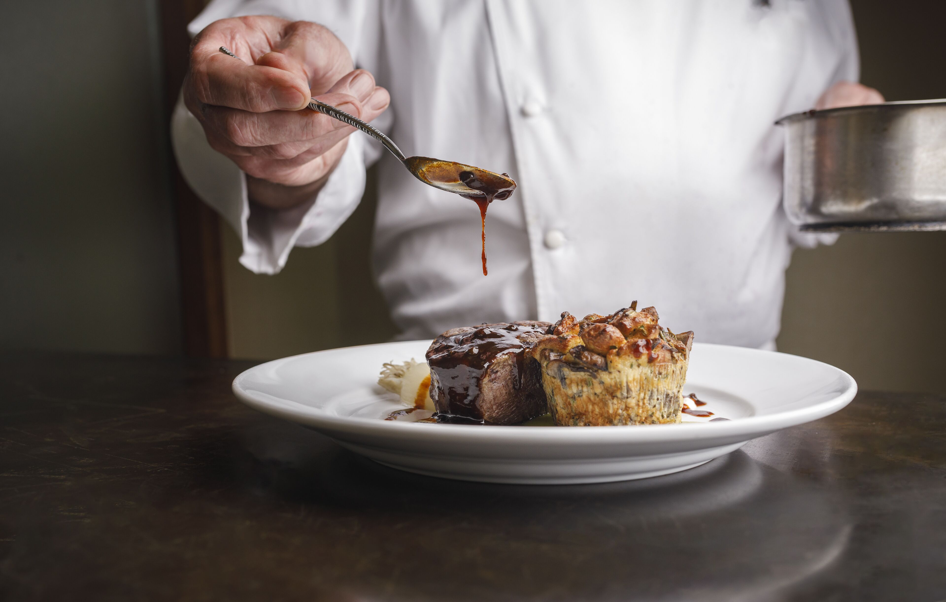 Un chef sirve un postre en un plato blanco.