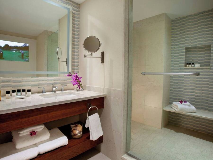 A modern bathroom with a large mirror, a sink, and a shower area.