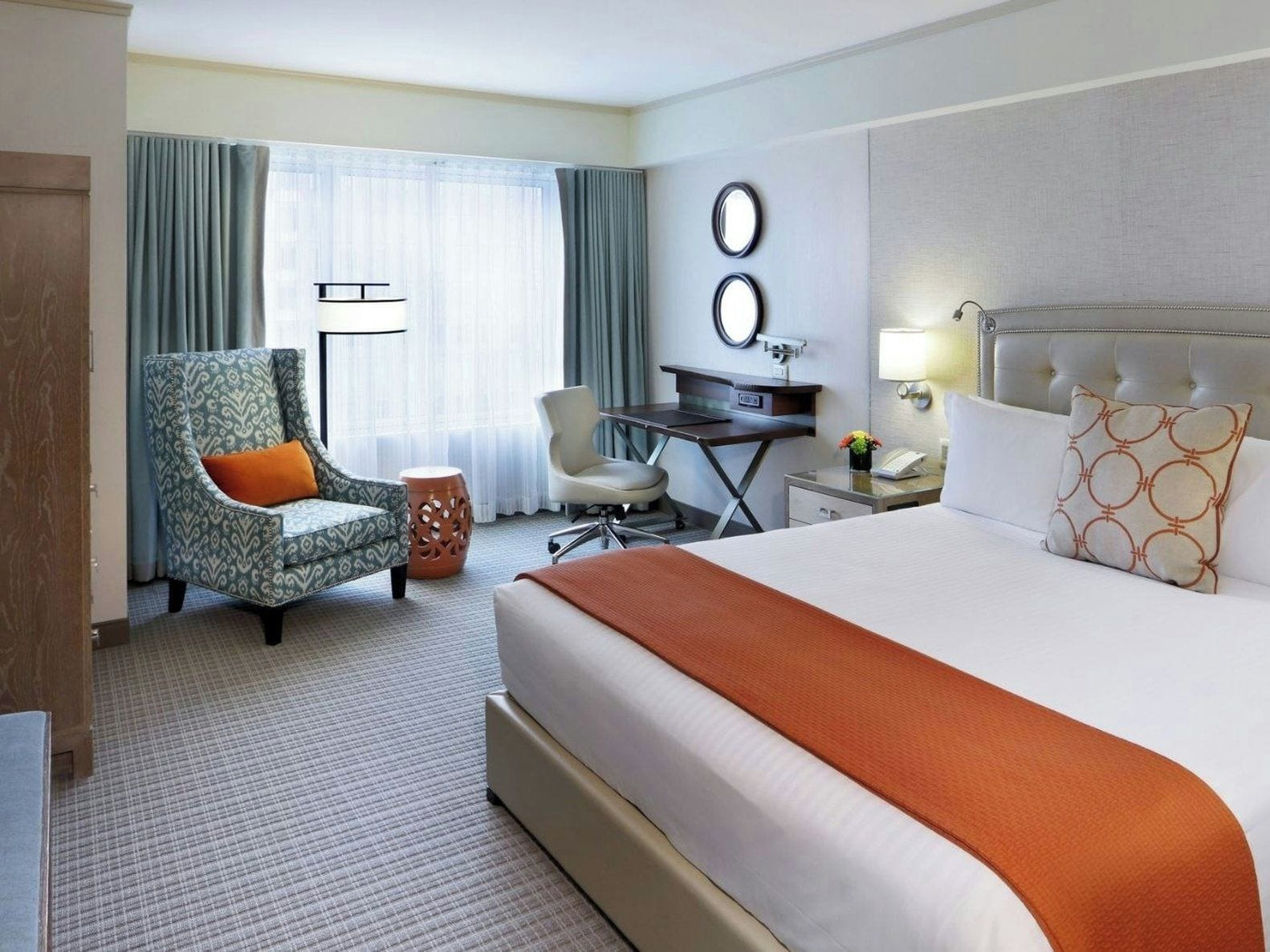 Ein Hotelzimmer mit einem Bett, einem Schreibtisch, einem Stuhl und einem kleinen Tisch.
