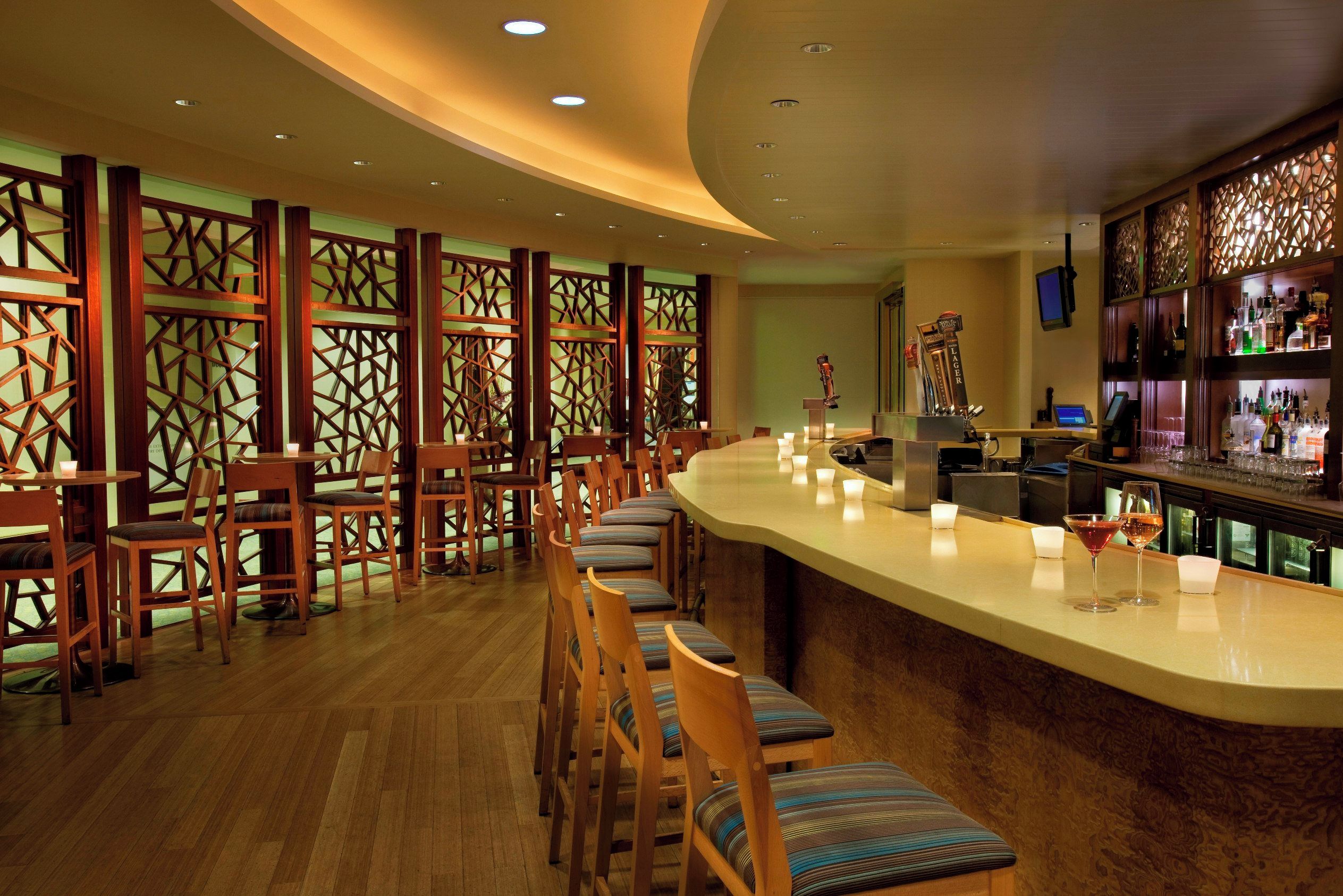 A bar area with wooden chairs and a counter, featuring a decorative partition and a beer tap.