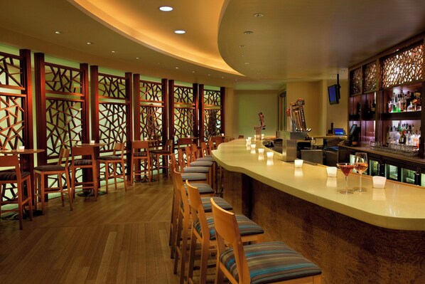 A bar area with wooden chairs and a counter, featuring a decorative partition and a beer tap.