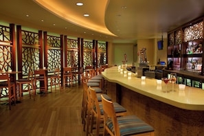 A bar area with wooden chairs and a counter, featuring a decorative partition and a beer tap.