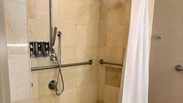 A shower area with a grab bar, a handheld showerhead, and a shower caddy.