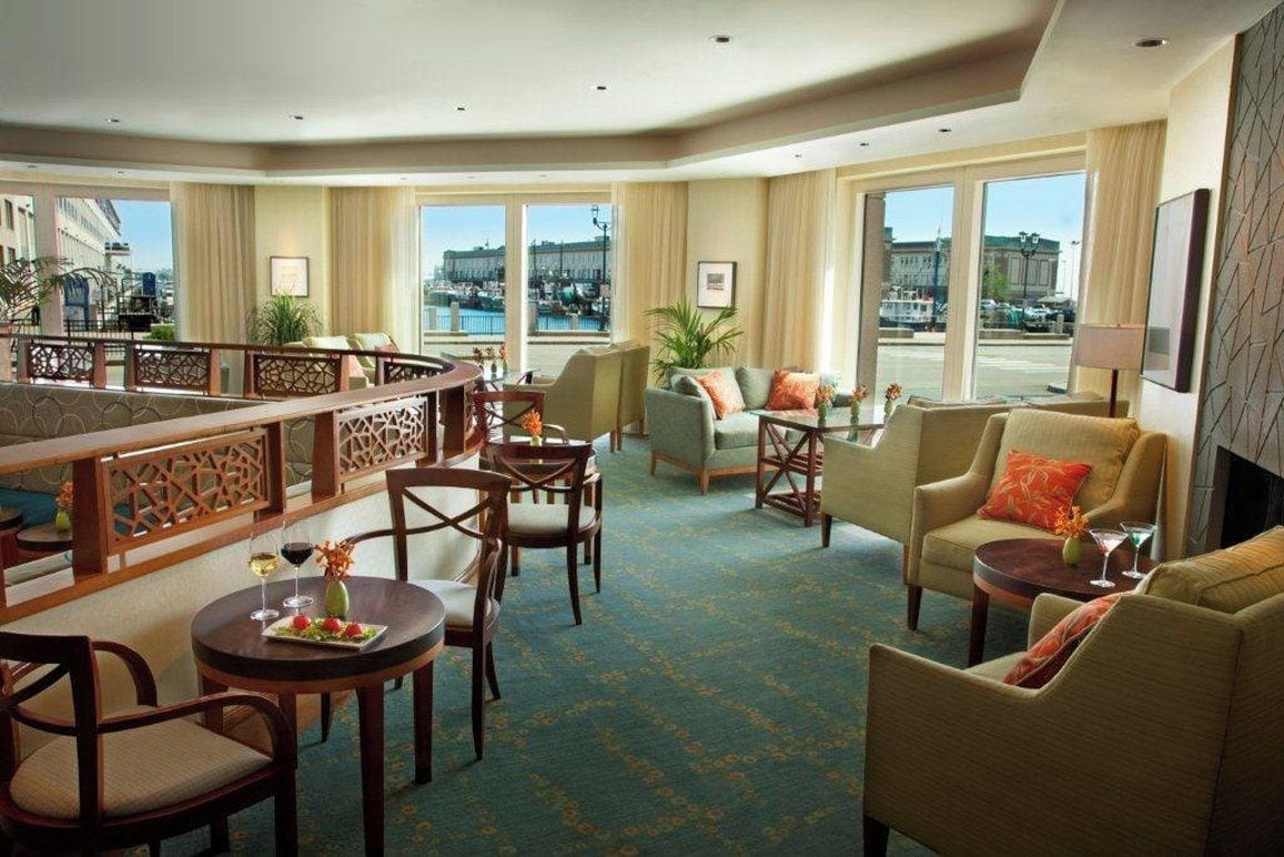 Una hall d'albergo con zona bar, posti a sedere e ampie finestre con vista sulla città.